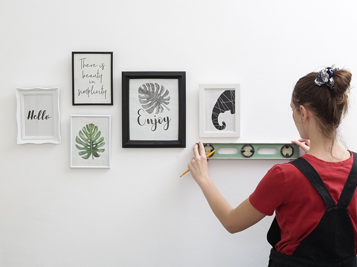 Woman arranging picture frames on wall in new house, diy home improvement concept