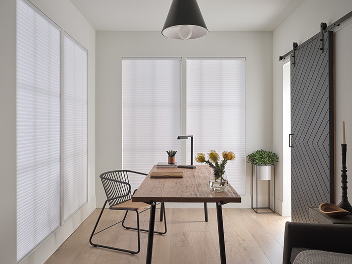 Bureau propre avec fenêtres ornées de stores en nid d’abeilles DuetteMD de Hunter Douglas.