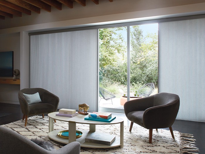 Coffee table and two accent chairs in front of large sliding glass door.